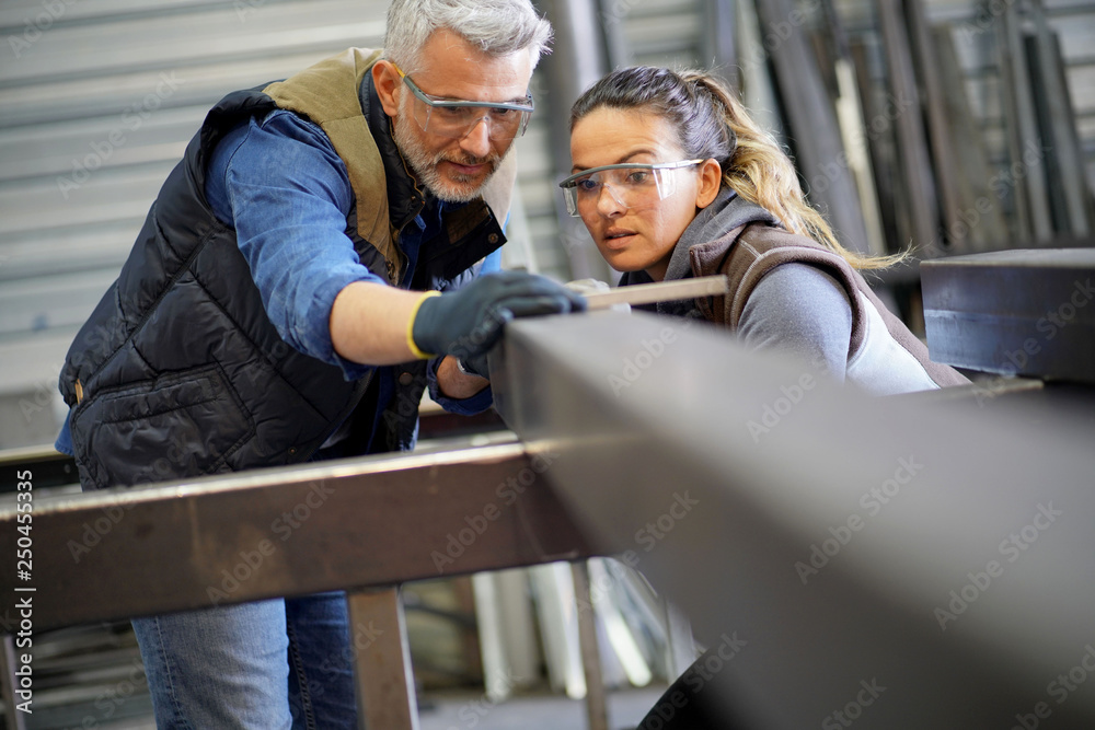 Metalworker with apprentice in workshop Metalworker with apprentice in workshop