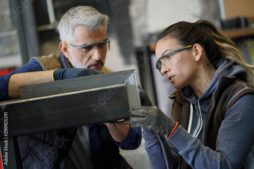 Metalworker with apprentice in workshop photo