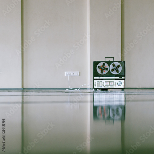 vintage analog magnet tape recorder standing on the floor near wall