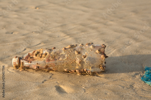 Plastic products clog nature more and more. Plastic bottle covered in sea barnacles and sponges (foulers) and cast ashore on the beach, marine pollution. Nature is fighting with the garbage