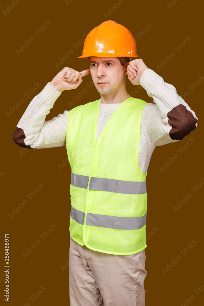 the man in a construction helmet, a vest closed ears hands not to hear noise the man in a construction helmet, a vest closed ears hands not to hear noise