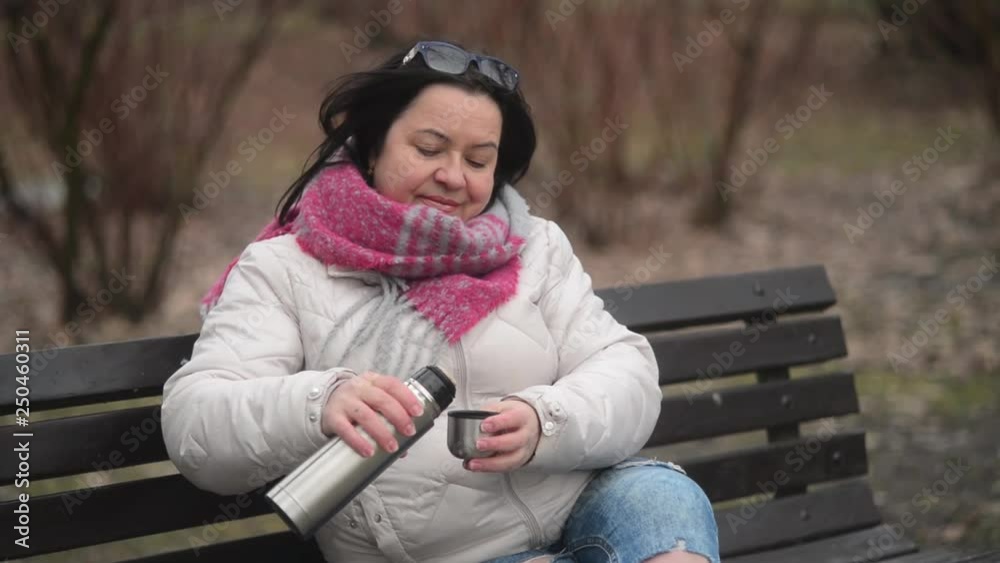 Portrait of a Mature Woman Lady drinking Tea from a Thermos in a Park at Winter Portrait of a Mature Woman Lady drinking Tea from a Thermos in a Park at Winter