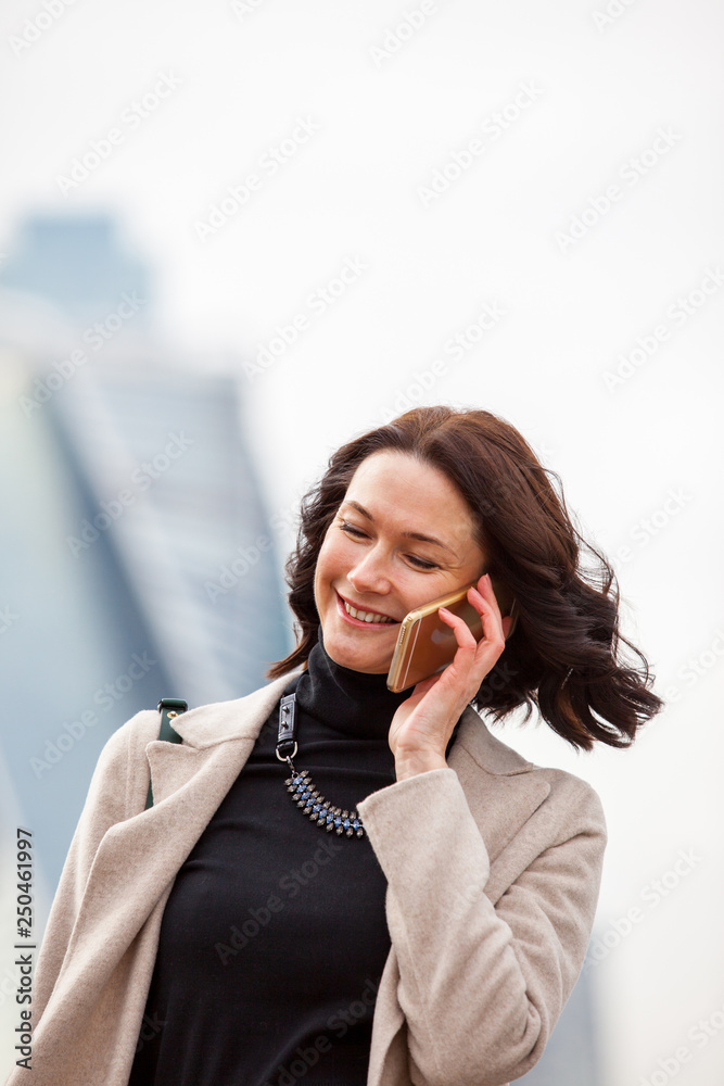 beautiful smiling woman talking on a mobile phone - obrazy, fototapety, plakaty 