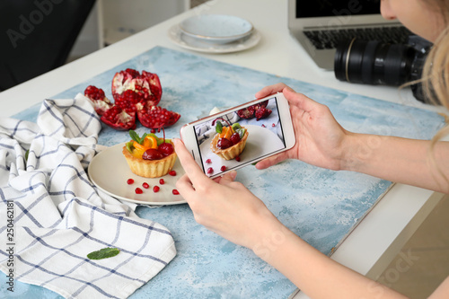 Female food photographer with mobile phone taking picture of tasty food