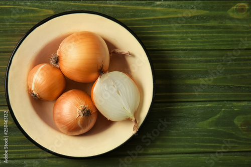 Plate with raw onion on wooden table