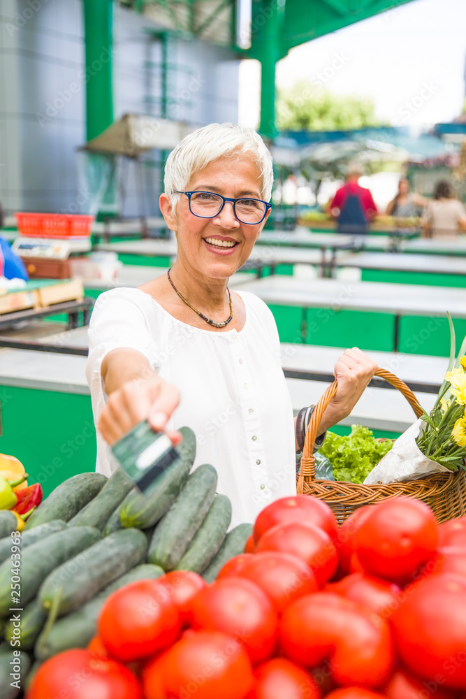 Fototapeta premium Senior woman holds credit card on market