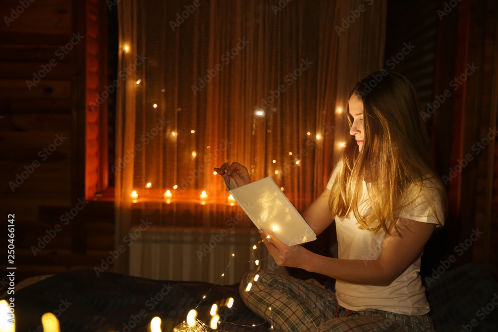 Beautiful woman reading fairy tales in darkness with glowing lights Beautiful woman reading fairy tales in darkness with glowing lights