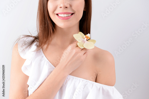 Beautiful young woman with orchid flower on white background