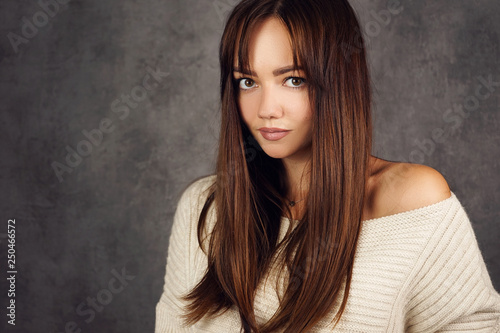 Beautiful girl with long hair in a sweater on a dark background 