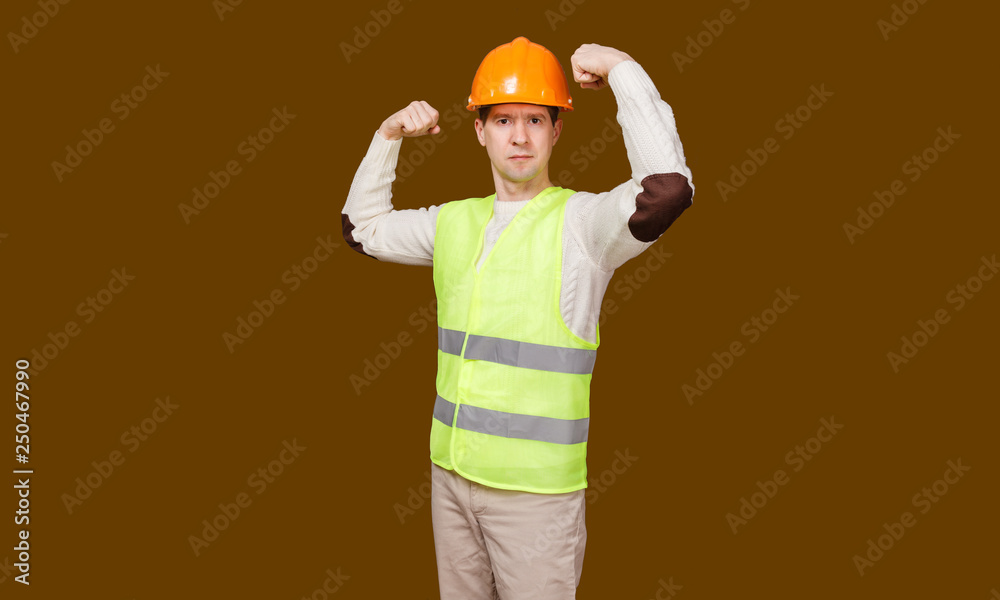 the man in a construction helmet, a vest shows force of a biceps of the hands bent in an elbow