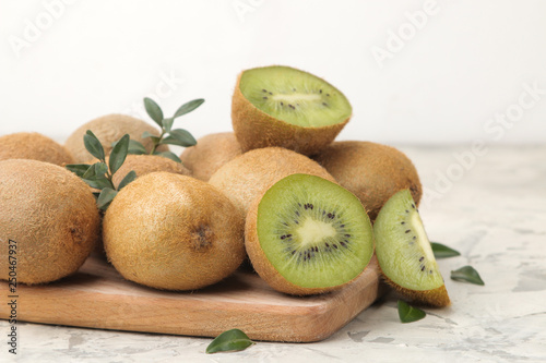 Delicious ripe lots of kiwi fruit and kiwi cut on a board on a light concrete background.