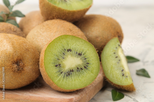 Delicious ripe lots of kiwi fruit and kiwi cut on a board on a light concrete background. close-up .