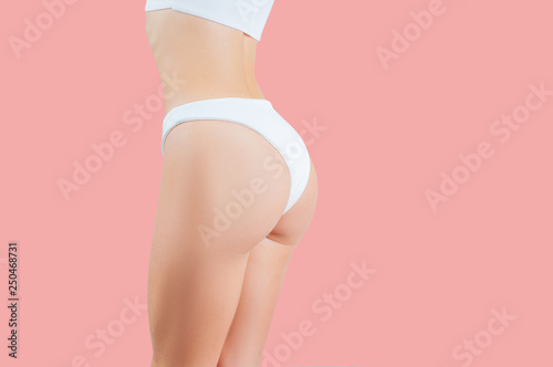 Beautiful woman showing perfect buttocks in white underwear on pastel pink background