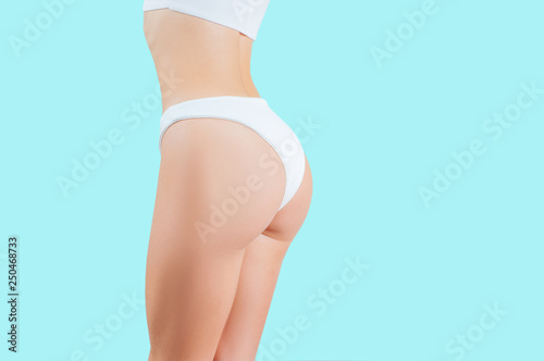 Beautiful woman showing perfect buttocks in white underwear on blue background