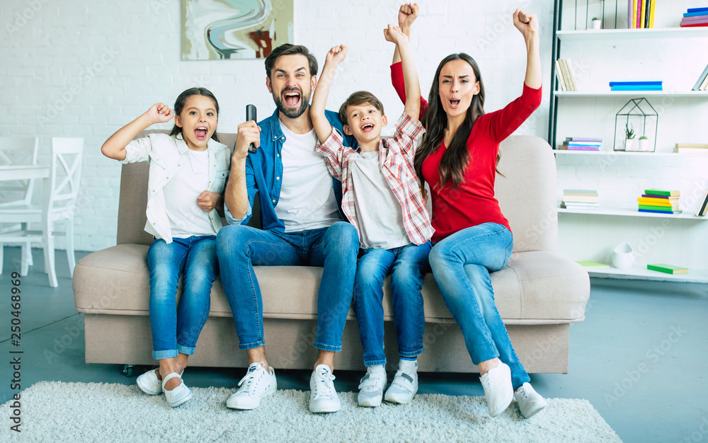 Excited big family team watch football match together on the couch at home Excited big family team watch football match together on the couch at home
