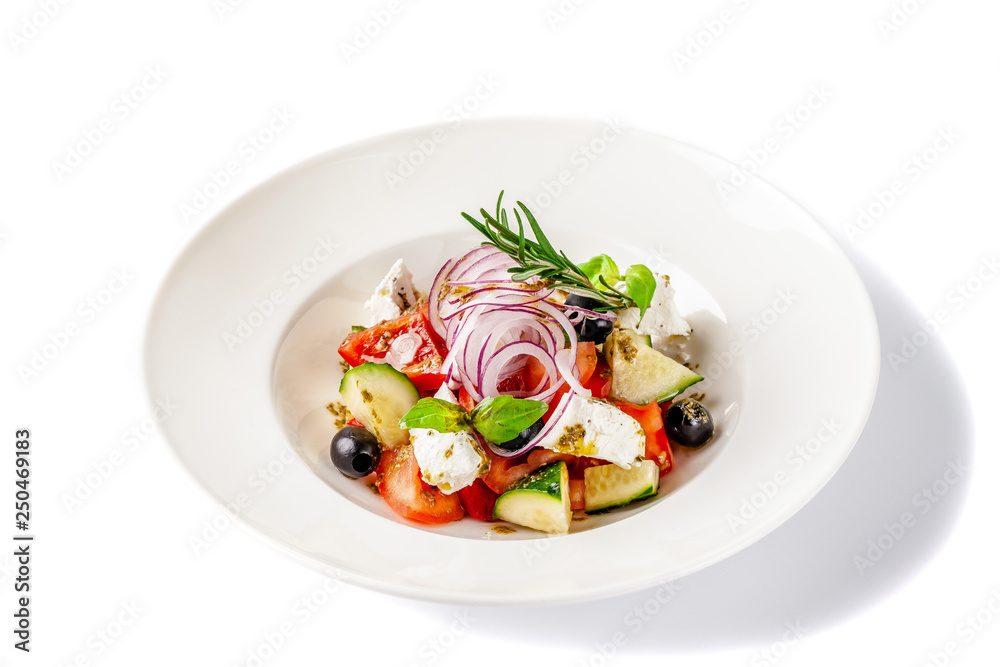 Concept of Greek cuisine. Salad of tomato, cucumber, bell pepper, olives and feta cheese. dressed with olive oil and decorated with fresh basil. White plate on a white background. Concept of Greek cuisine. Salad of tomato, cucumber, bell pepper, olives and feta cheese. dressed with olive oil and decorated with fresh basil. White plate on a white background.