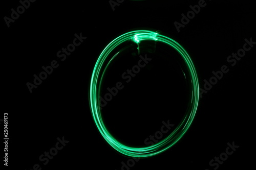 Long exposure, light painting photography.  Abstract circle outline design, vibrant green color against a black background