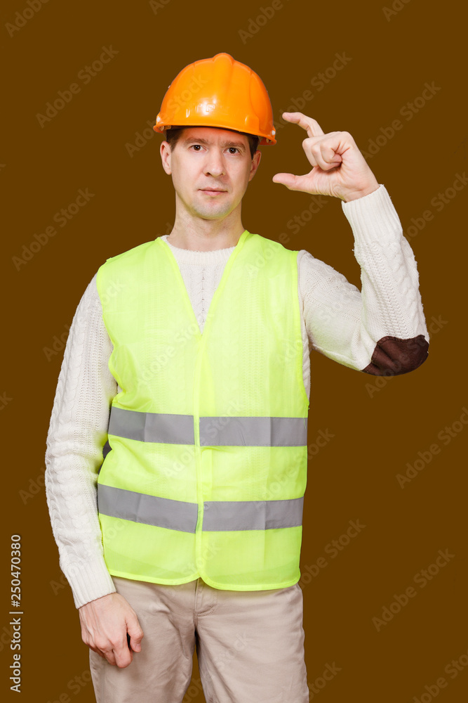 the man in a construction helmet, a vest, shows fingers big and index the size