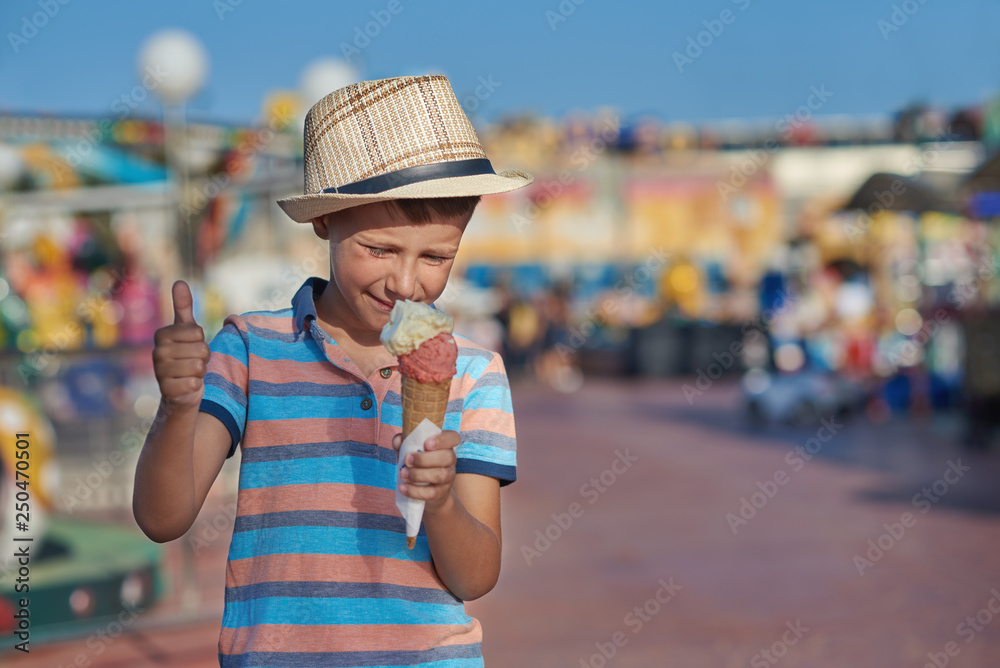 Cute boy is eating ice-cream he is enjoying his summer holidays and making like gesture.
