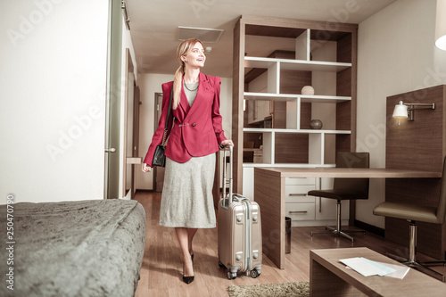 Blonde-haired woman coming to hotel room with her luggage