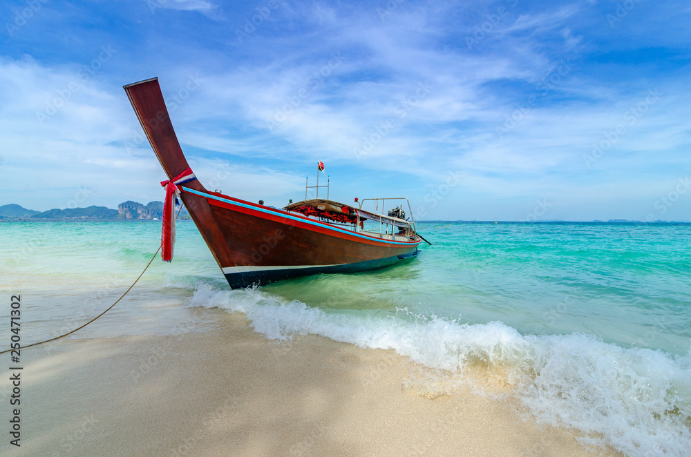 Wooden boat parked on the sea, white beach on a clear blue sky, blue sea