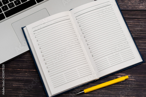 Opened clean business notebook and laptop. Business notebook for record important events and meetings with business partners on the wooden table