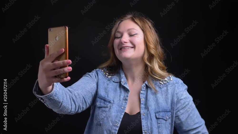 Closeup portrait of adult caucasian female with short blonde hair having a video call on the phone smiling and casually waving hello