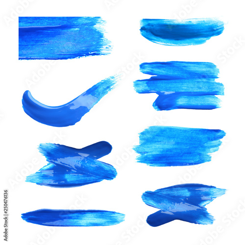 Set with abstract brushstrokes of blue paint on white background, top view