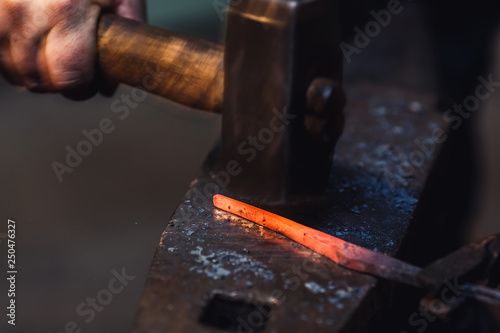 blacksmith makes an artistic forging of hot metal on the anvil.