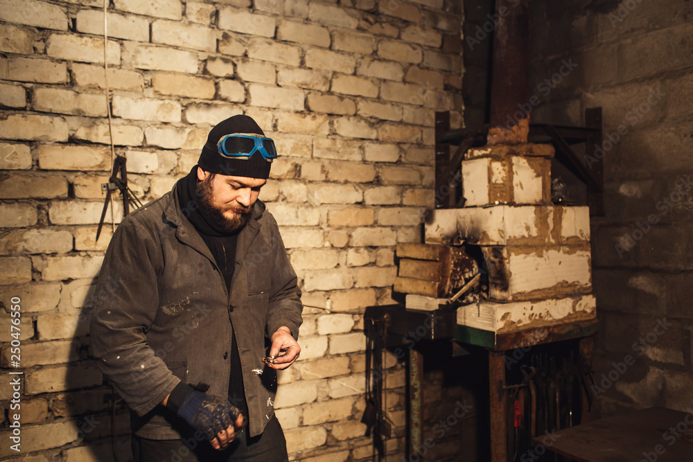 Fototapeta premium bearded blacksmith fires fire with firesteel and flint.