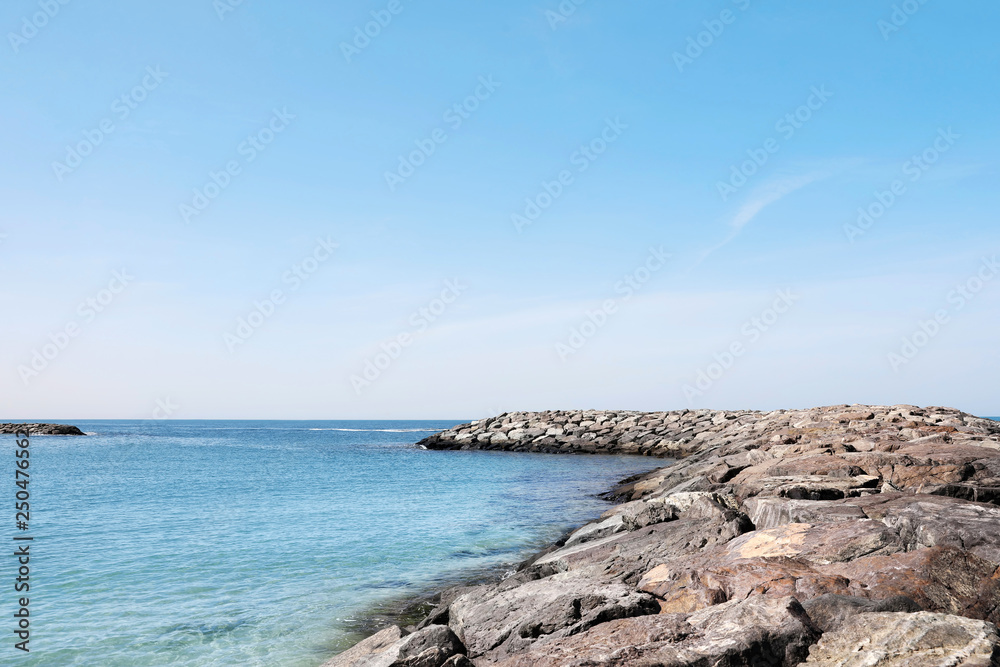 Picturesque view of beach with stone breakwater on sunny day