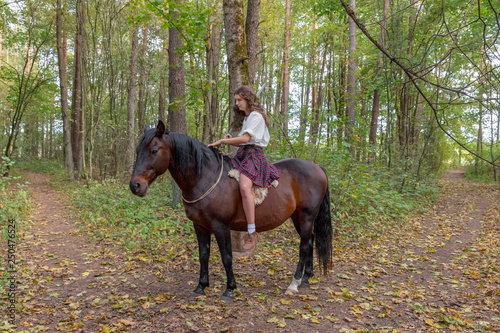Girl in a Scottish kilt on a horse, holding a sword in her hand