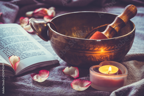 Fotografija Tibetan singing bowl with book candel and rose petal
