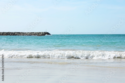 Picturesque view of beach with stone breakwater on sunny day