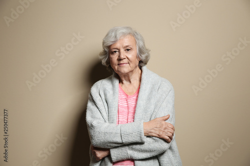 Portrait of elderly woman on color background