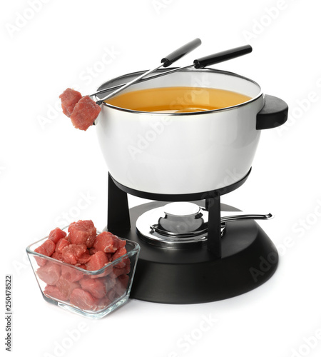 Fondue pot with oil and raw meat on white background