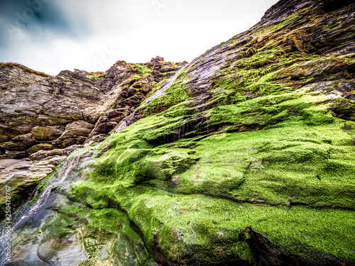 Beautiful waterfall over mossy stones in the Cove of Tintagel in Cornwall