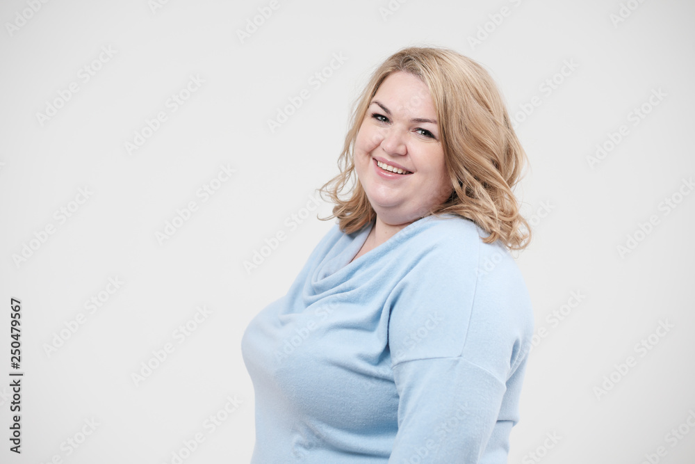 Young obese woman in casual blue clothes on a white background in the studio. Bodypositive. Young obese woman in casual blue clothes on a white background in the studio. Bodypositive.