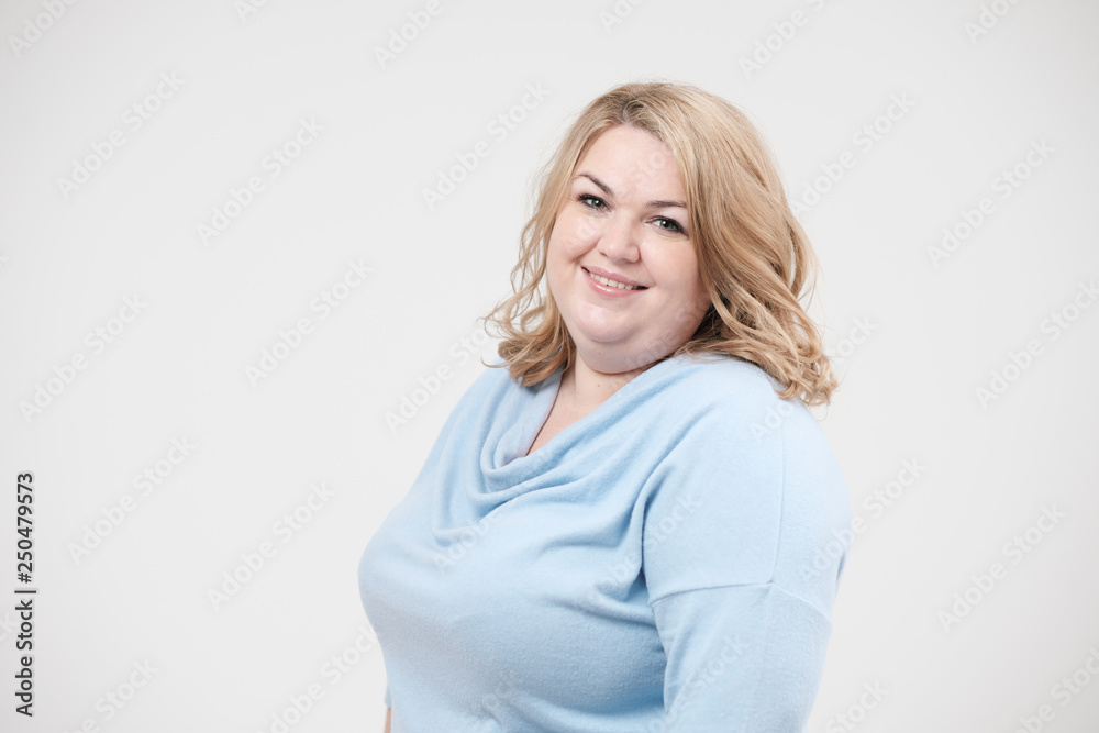 Young obese woman in casual blue clothes on a white background in the studio. Bodypositive. Young obese woman in casual blue clothes on a white background in the studio. Bodypositive.