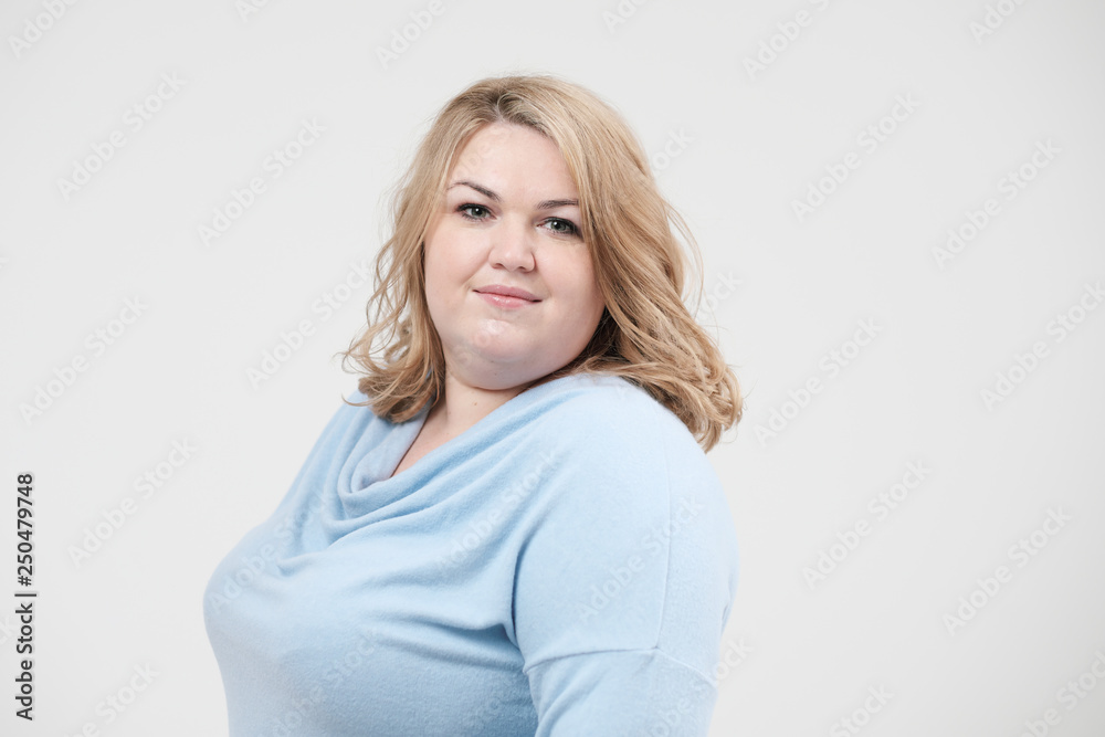 Young obese woman in casual blue clothes on a white background in the studio. Bodypositive. Young obese woman in casual blue clothes on a white background in the studio. Bodypositive.