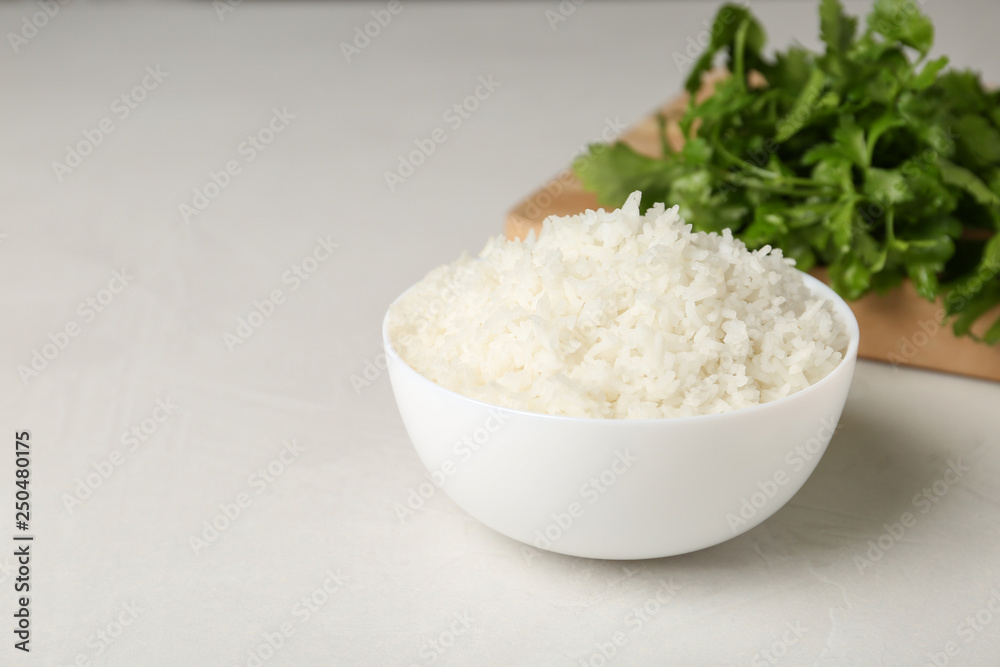 Bowl of boiled rice on light table. Space for text