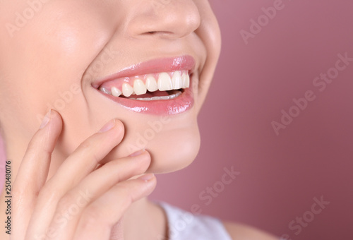Young woman with healthy teeth and beautiful smile on color background, closeup. Space for text