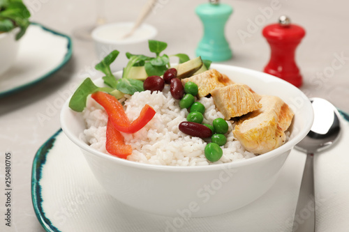 Bowl of boiled rice with vegetables and meat on table