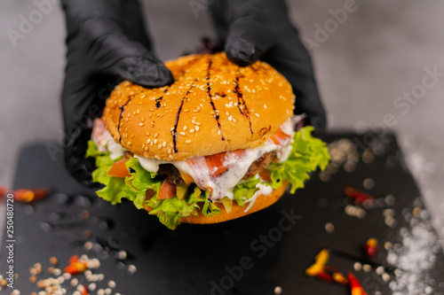 Burger in the hands on a dark background