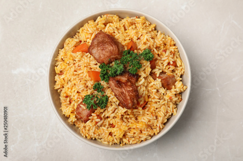 Bowl with delicious rice pilaf on light background, top view