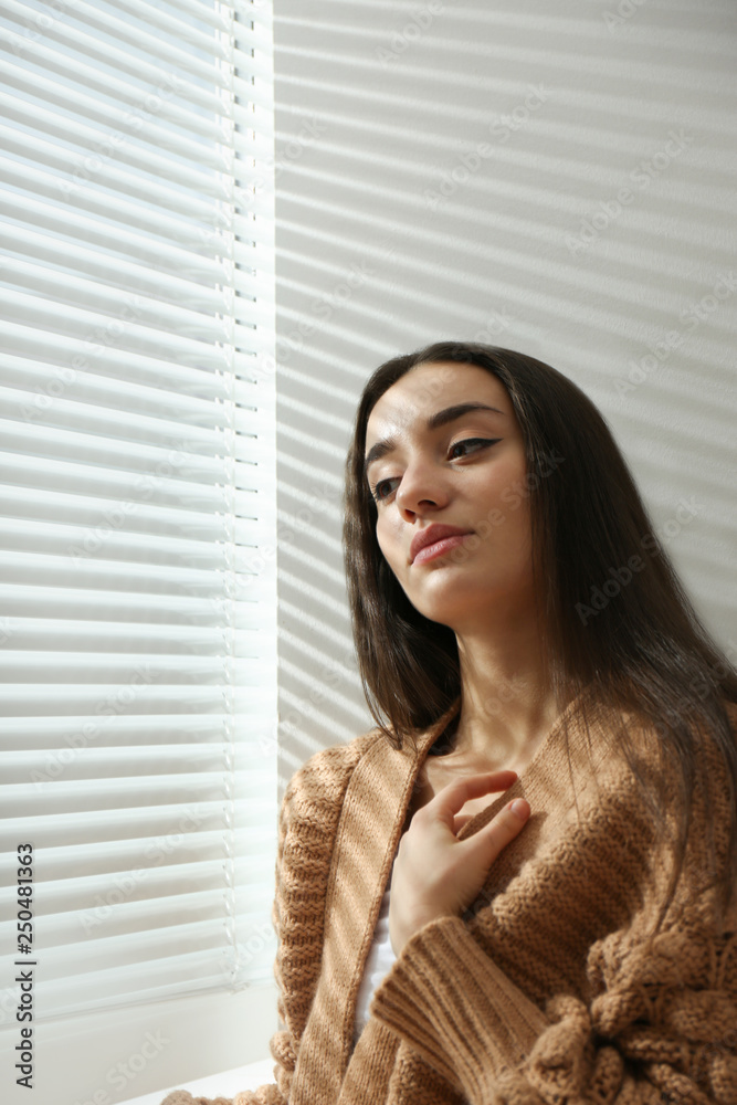 Young woman near window with Venetian blinds Young woman near window with Venetian blinds