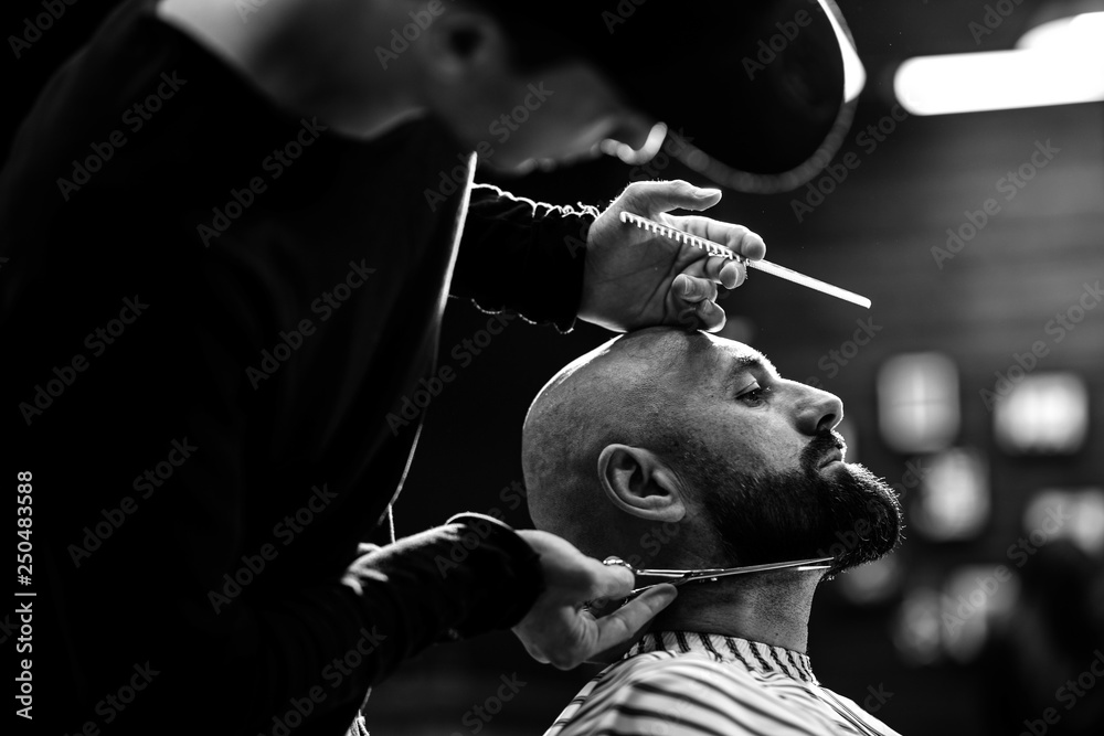 Black and white photo. Fashion barber dressed in a black clothes tidies