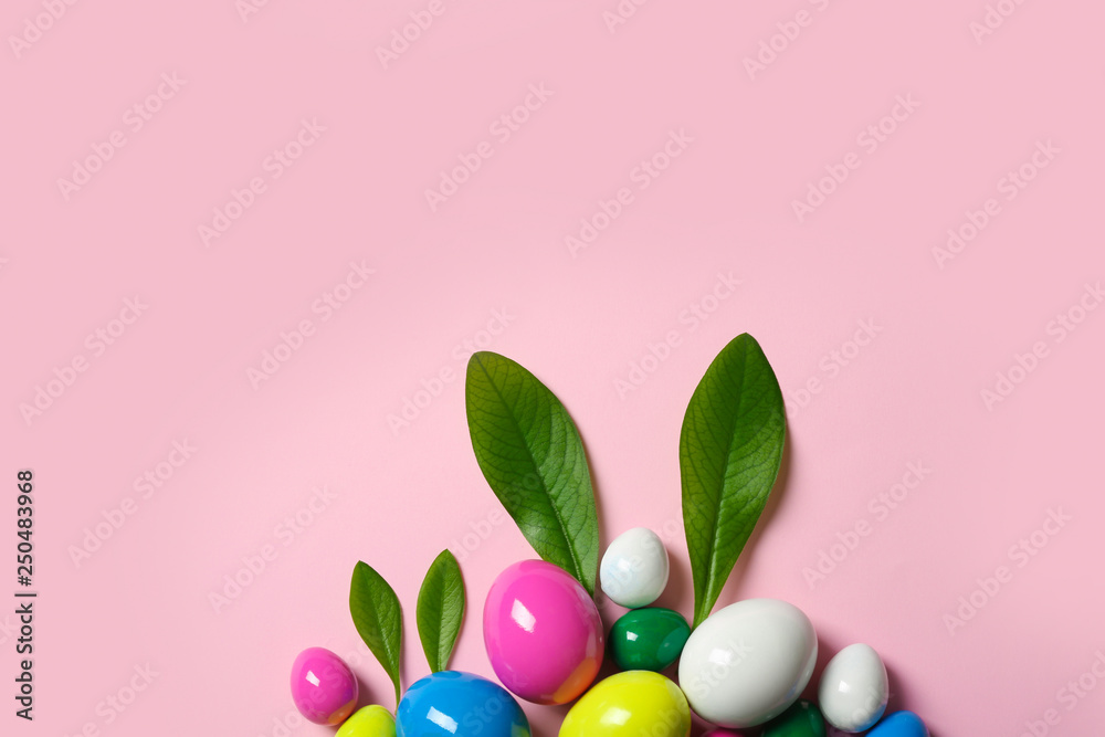 Creative flat lay composition with Easter bunny ears made of green leaves and eggs on color background, space for text