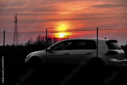 VICENZA, ITALY - January 28, 2019: White hatchback car Golf park behind a metal net with the sunshine in a background. Color toning modified in post-production.