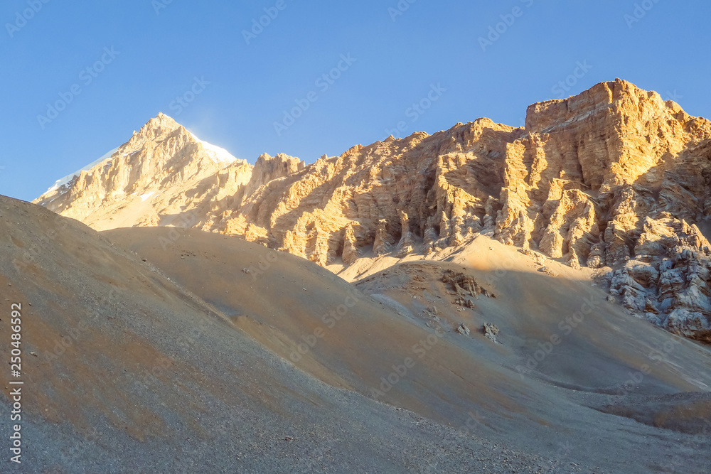 Fototapeta premium Himalayas Mountain Range, Annapurna Circuit Trek, Nepal. Clear sky above the peaks. Slopes covered with limestone rocks. Serene landscape. Dangerous mountains. Morning sun comes to the high parts